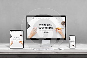 Web design studio with multiple devices on office desk. Concept of responsive, flat web page design
