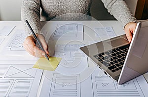 Web designer working at laptop and website wireframe sketches