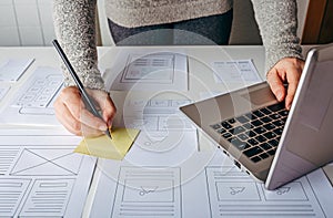 Web designer working at laptop and website wireframe sketches photo