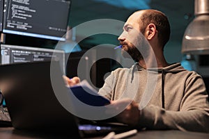 Web developer analyzing source code with papers