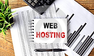 WEB HOSTING text on a notebook with chart and calculator
