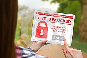 Web site blocked concept, girl holds the digital tablet on blurred nature background