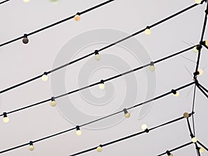 Web of wires of festive lighting with vintage light bulbs on the background of the cloudy sky in the evening