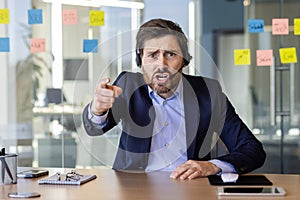Webcam view, angry man with headset phone yelling at webcam, computer screen, businessman arguing with colleagues and