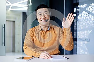 Webcam view, portrait of successful tech support and customer service worker, man smiling and looking at camera waving