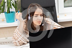 Webinar online. A student at home is studying with headphones with a microphone, trying to understand the lecture