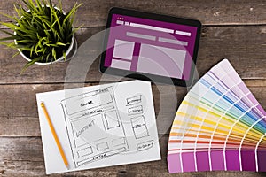 Website wireframe sketch and digital tablet on wooden table