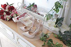 A bride`s bouquet of red and pink roses, women`s shoes, a garter of the bride