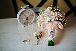 Wedding accessories. Boutonniere, Golden rings, a beautiful bouquet of flowers on white textured table. Concept of bride