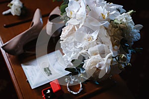Wedding accessories: bridal bouquet, two buttonholes, women`s shoes, wedding rings in a box, women`s bracelet, envelope with a