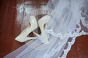 Wedding accessories. Bridal shoes  and veil on the wooden floor at wedding morning preparation
