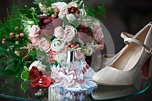 Wedding accessories for the bride and groom: a bouquet of red, pink and white roses, a boutonniere, gold wedding rings, a lace gar