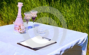 Wedding accessories and champagne with glasses for marriage in summer park