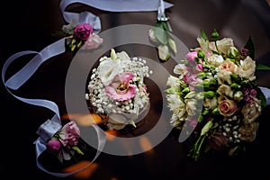 Wedding accessory bride. Stylish beige shoes, earrings, gold rings, flowers, garter, perfumes on table standing on wooden