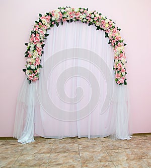 Wedding arch as the place of artificial flowers, decorated with fabric