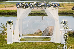 The wedding arch is decorated with blue flowers and white light silk. Summer Wedding Ceremony