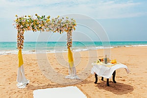 Wedding arch decorated with flowers on a tropical sand beach. Outdoor beach wedding setup