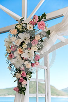 Wedding arch detail - pink and white flowers arranged with an ethereal veil against blue sky