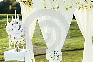 Wedding arch with flowers and ÃÂandle decoration on sunny day in ceremony place