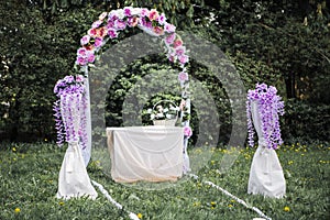 Wedding Arch with pirple and pink flowers on the grass photo