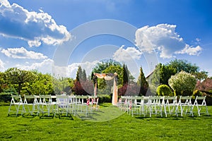 Wedding arch and white chairs on nature background