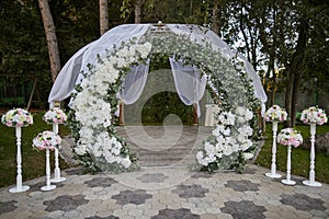 Wedding arch of white flowers and tulle in nature