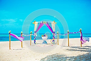 Wedding archway are arranged on the sand in preparation for a beach wedding ceremony.