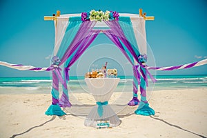 Wedding archway are arranged on the sand in preparation for a beach wedding ceremony.