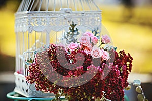 A wedding arrangement, pink roses and white cage