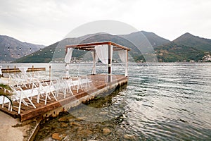 Wedding awning on the pier in front of a row of chairs. Side view