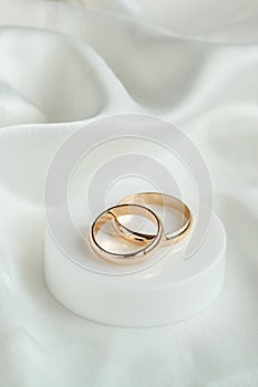 Wedding background with two gold rings on white satin material. Marriage