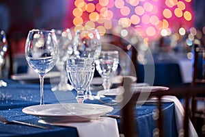 Wedding. Banquet. The chairs and round table for guests, served with cutlery and crockery and covered with a blue photo