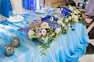 Wedding banquet decoration. Artwork. Soft focus on the bouquet with eustoma and blue hydrangeas on a blue tablecloth