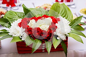 Wedding. Banquet. Flowers. The composition of red, white and green, standing on a table in the area of wedding party.