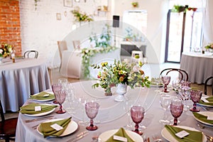 Wedding banquet, served tables with flowers and lots of greenery