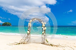 Wedding on the beach . Wedding arch decorated of vines and flowers on tropical sand beach. Wedding and honeymoon concept.