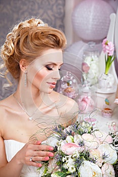 Wedding. Beautiful bride with bouquet in bedroom