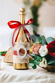 Wedding bottle of champagne painted in gold is decorated in a rustic style