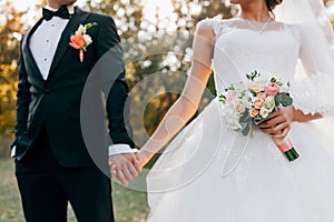 Wedding bouquet. Blurred bride with in a white dress and groom in tuxedo are holding hands. Soft focus on flowers