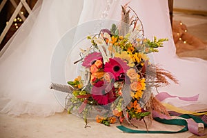 Wedding bouquet in boho style on the background of a wedding dress close up