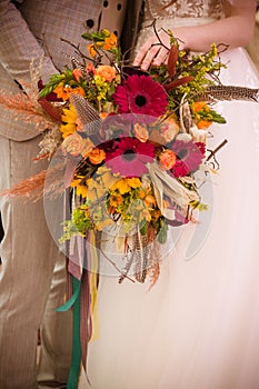 Wedding bouquet in boho style is held by newlyweds