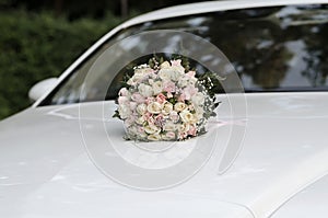 Wedding bouquet of the bride on the hood of the car