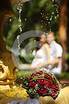 The Wedding Bouquet Of The Bride Of Red Roses Lies In An Old Fountain Under Splashes And Drops Of Water.