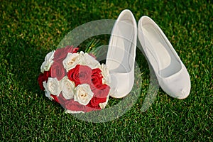 Wedding bouquet and the bride's white shoes on grass