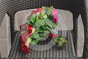 Wedding bouquet with bright red flowers and ribbon with a silver brooch on the stalk. Close-up. Artwork