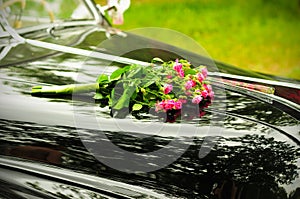 Wedding bouquet on cowl of black car