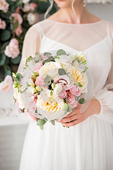 Wedding bouquet with cream and pink roses in the hands of the bride. Delicate flowers close-up. Spring bouquet