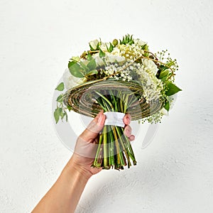 Wedding bouquet created on a frame of green branches in a hand of woman