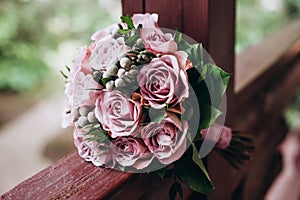 The wedding bouquet of fiancee from the roses of tender tints lies on a wooden parapet