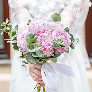 Wedding bouquet of flowers of pink peony in the hands of the bri